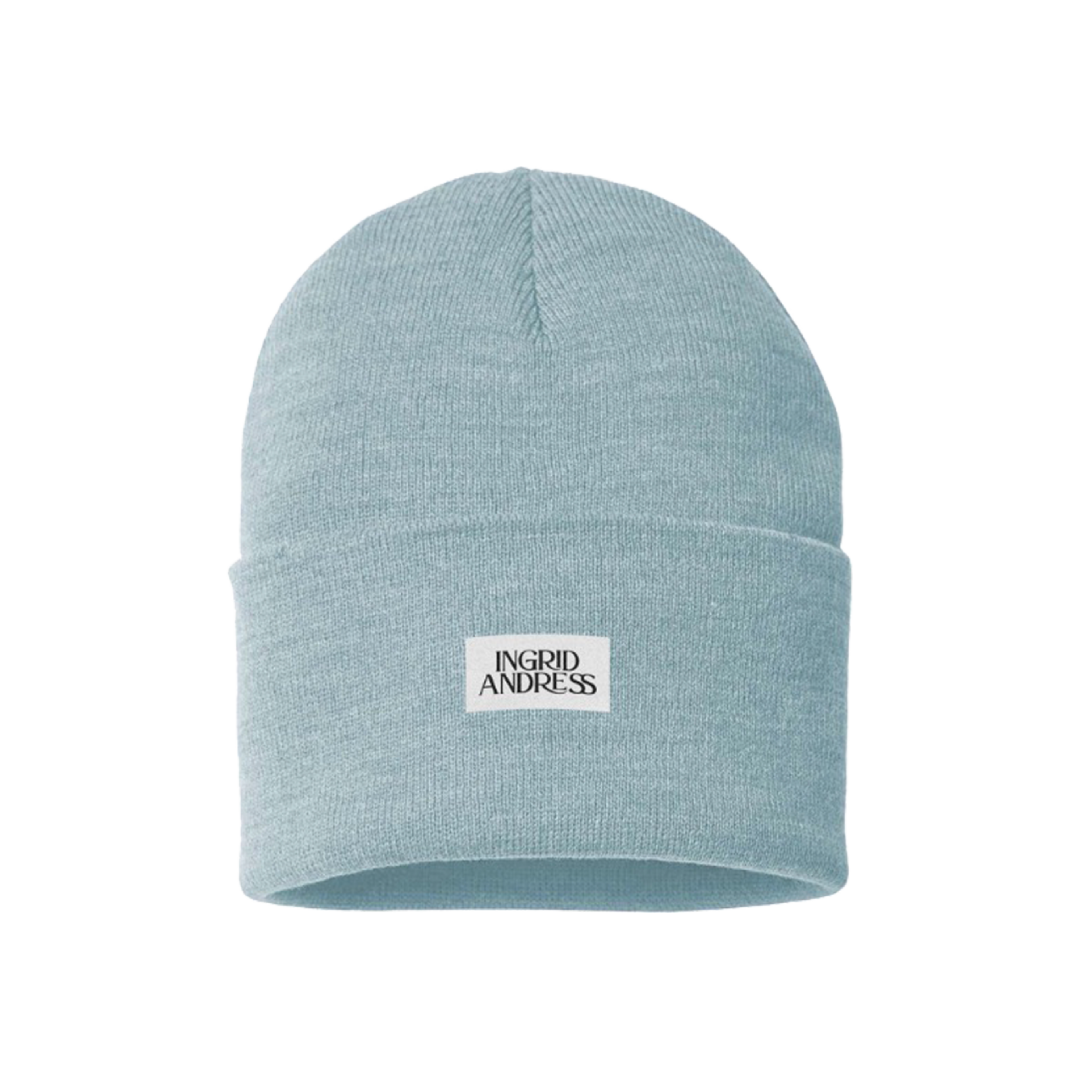 A light blue beanie with a branded patch on the front displaying the name 'Ingrid Andress'.
